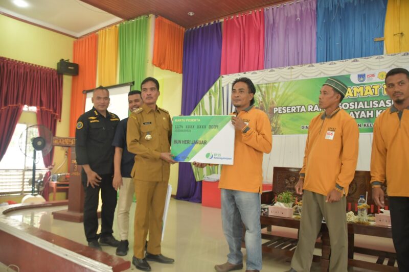 Pj Walikota Langsa Syaridin secara simbolis memberikan kartu BPJS Ketenagakerjaan kepada salah satu pemilik kebun sawit.