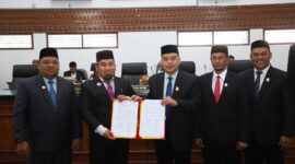 Pj Bupati Aceh Besar Muhammad Iswanto SSTP MM, dan Ketua DPRK Aceh Besar Abdul Muchti Amd, memperlihatkan Nota Kesepakatan KUA-PPAS R-APBK 2025 yang telah ditandatangani, pada Rapat Paripurna ke-13 DPRK Aceh Besar yang digelar di Gedung DPRK Aceh Besar, Kota Jantho, Kamis (31/10/2024).