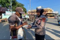 Salah seorang Polwan Satlantas Polres Lhokseumawe memberikan nasi kotak kepada warga yang membutuhkan 