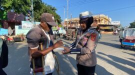Salah seorang Polwan Satlantas Polres Lhokseumawe memberikan nasi kotak kepada warga yang membutuhkan 